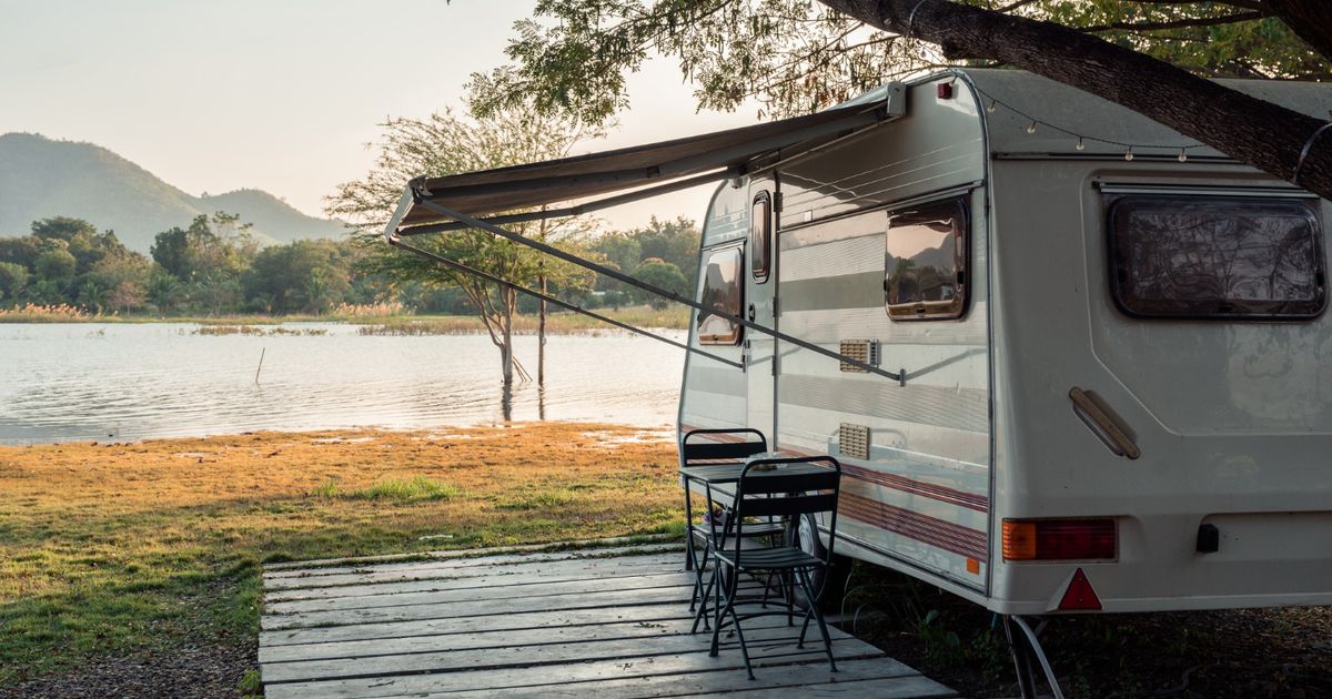 A white and brown camper in front of a lake