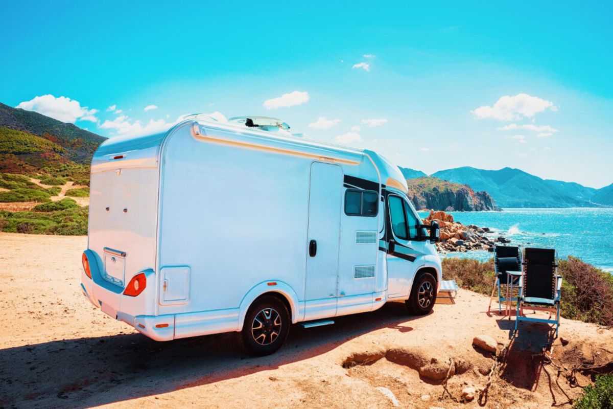 a white camper van in front of a beach of a RV park