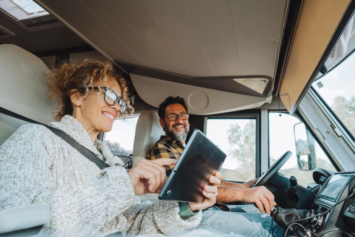 a woman holding a tablet with her husband checking their reservation in a RV park using their trusted software for campgrounds