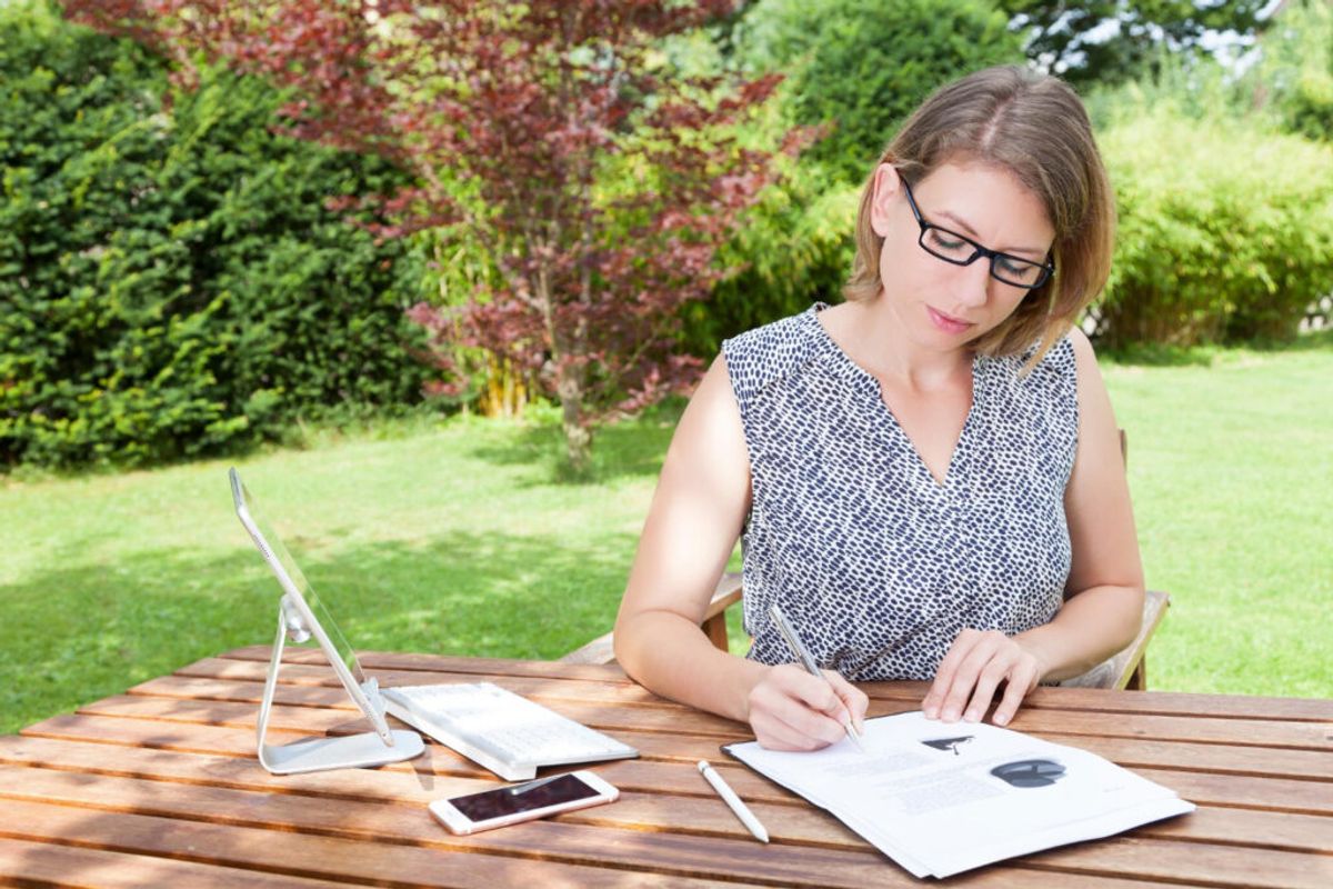 Woman in a blue shirt an Ipad and her phone calculating prices of her campground
