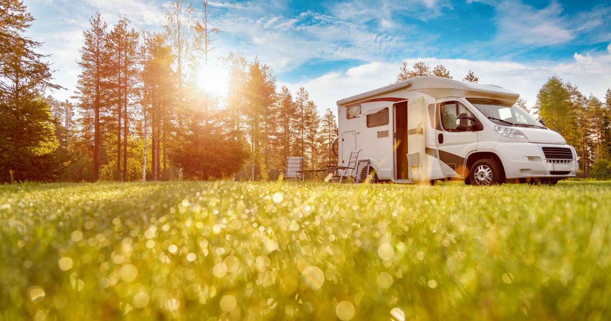 a low POV of a camper van with the grass and a blue sky
