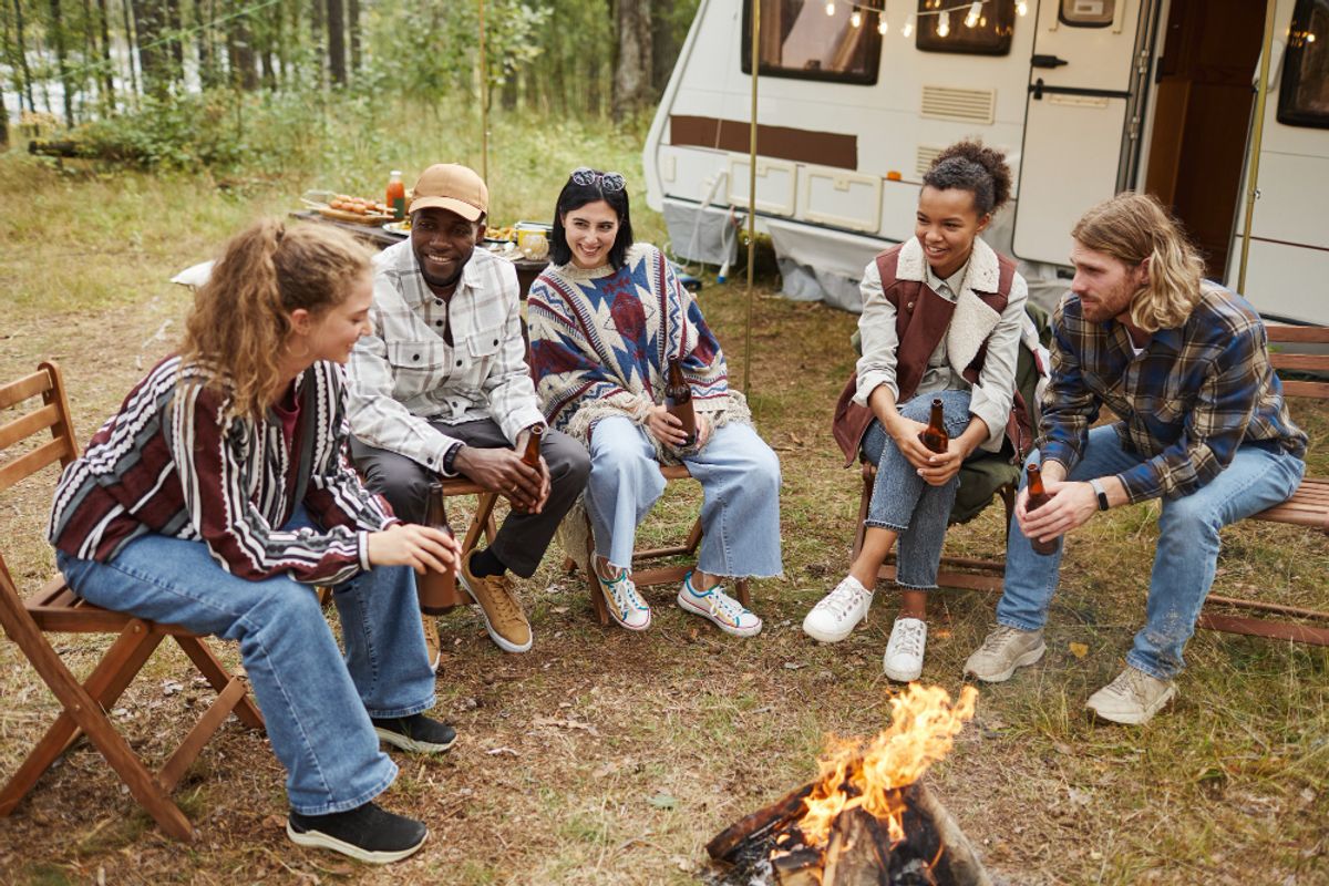 Group travelers enjoying their stay in a campsite in front of a campfire
