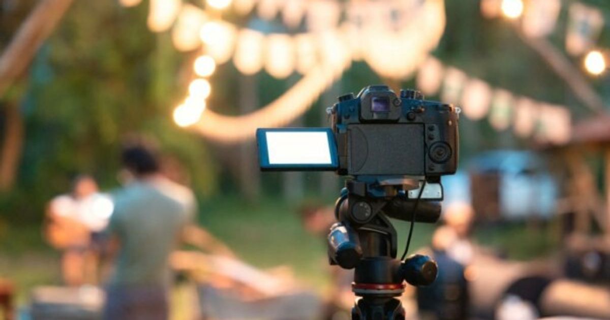 Camera recording standing on tripod with defocused illuminated live music concert event and camping background