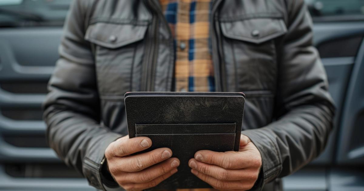 Person in gray jacket holding empty black wallet, symbolizing financial concern or budget constraints for campground pricing decisions.