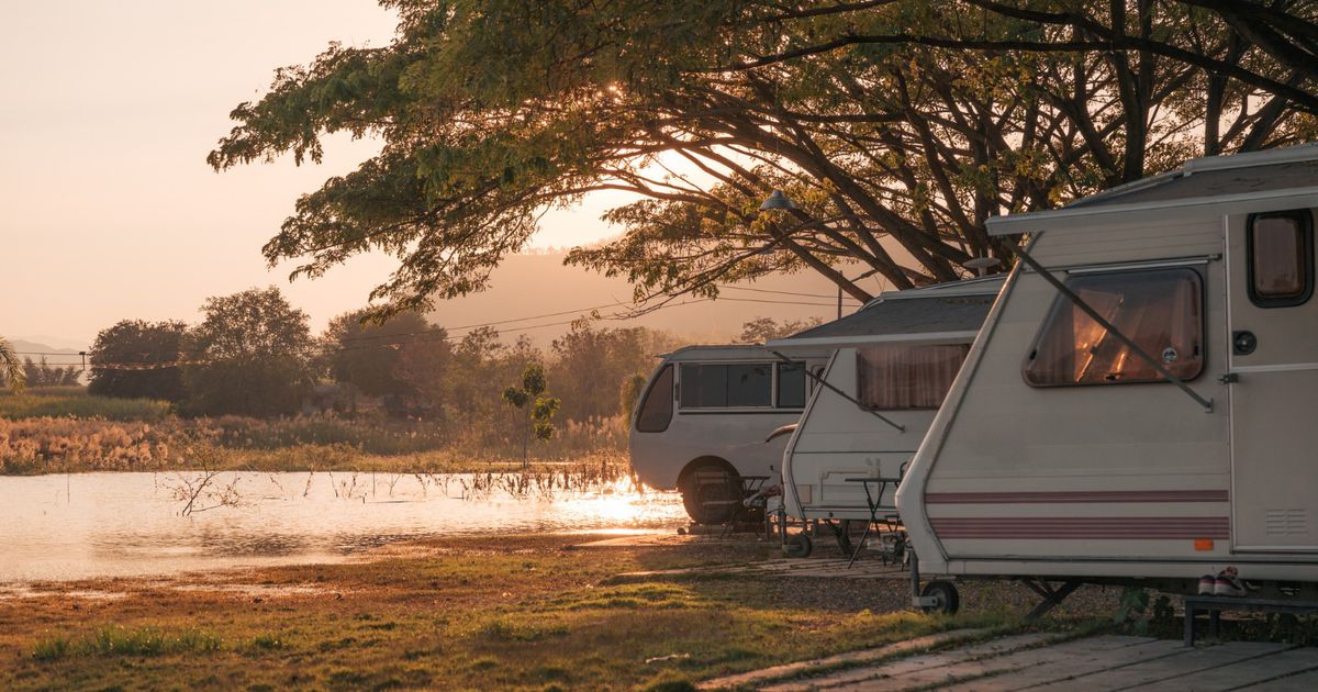 A group of campers in a campground in front of a lake at sunset