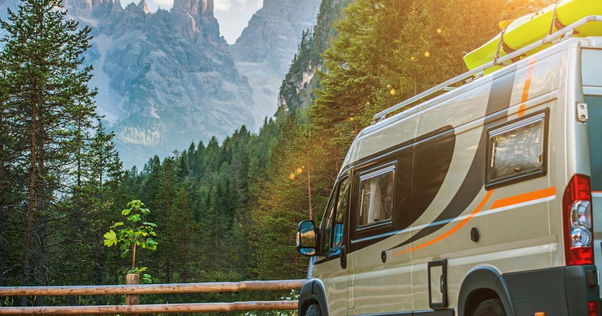 A grey camper van staying in front of a mountain