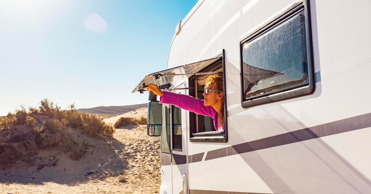 woman holding her window of a camper van in a RV park spot