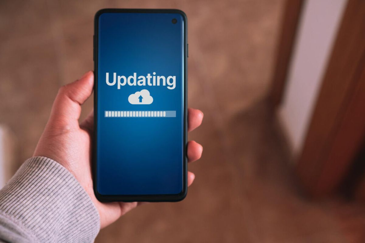 A person holding a phone that says "Updating" 