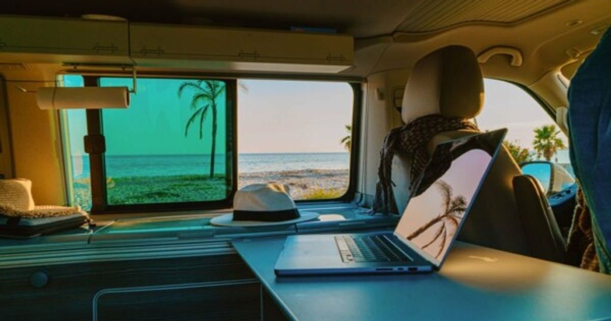 Close-up of laptop with reflection on screen in motor home against sea during summer