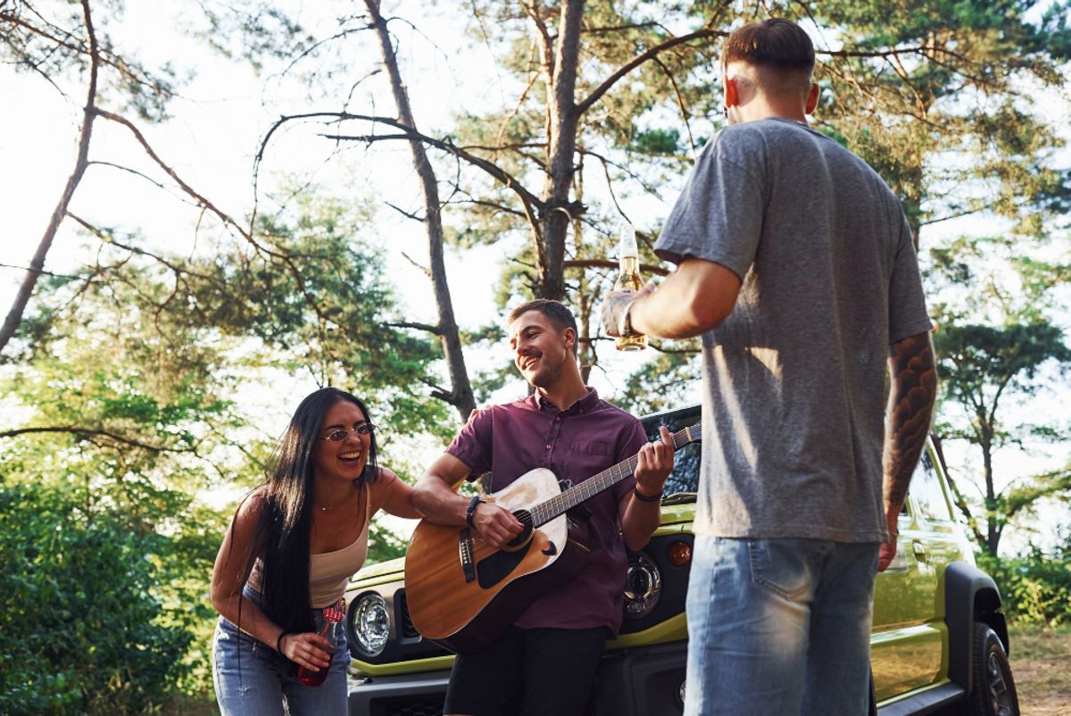 three friends enjoying the music of a guitar in the forest