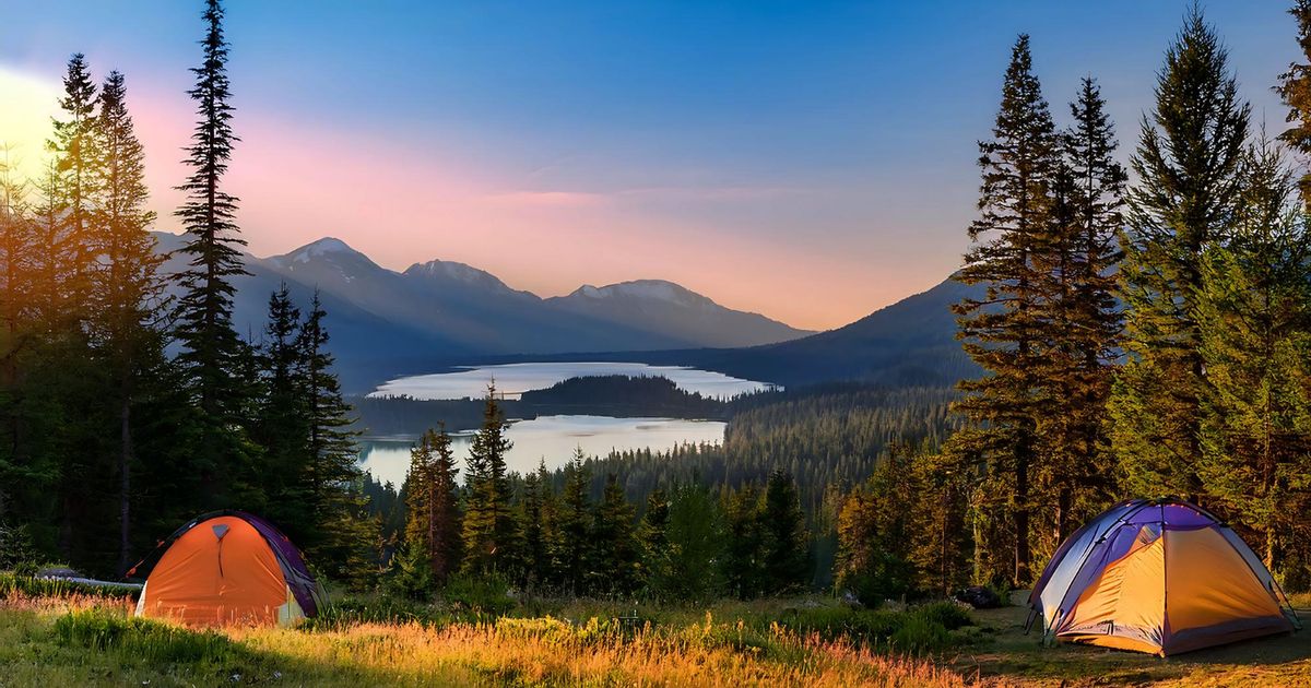 a panoramic view of a camping in the forest on a mountain with the sunet to the left