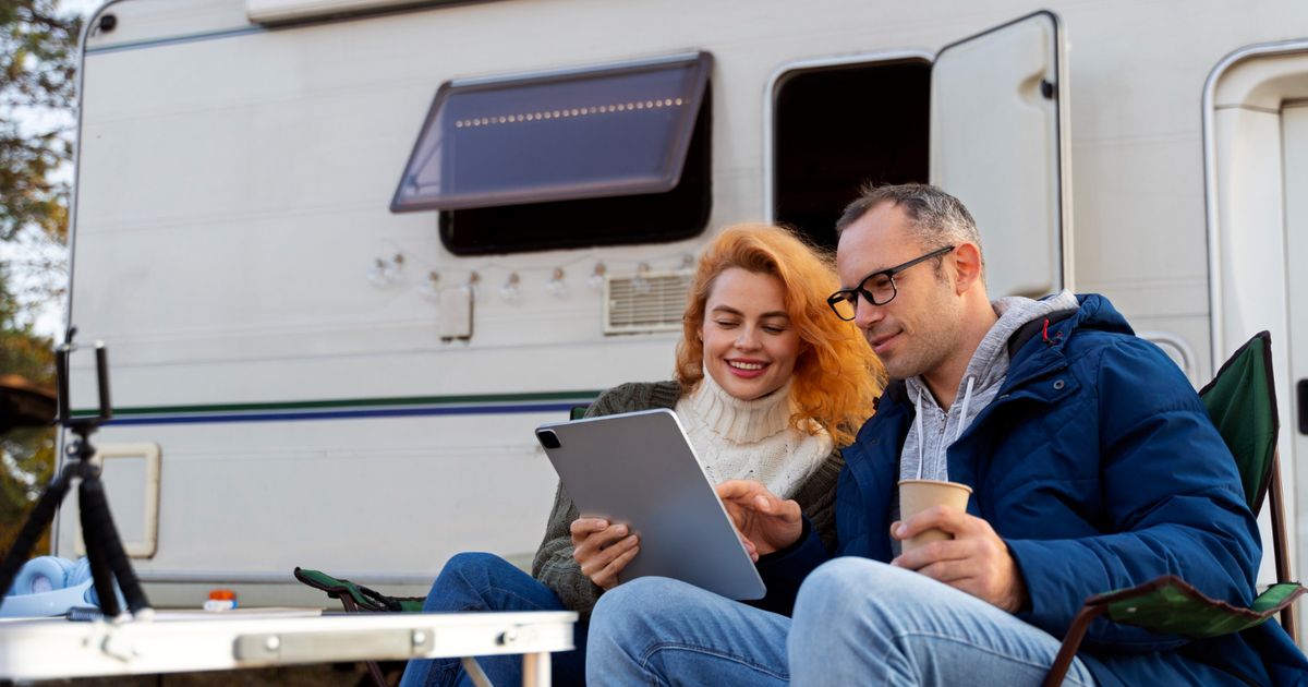 two people using a campground reservation software in front of a white camper