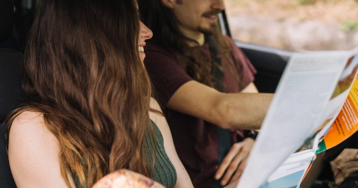 Two people reviewing maps and documents together inside a vehicle during a road trip or property scouting expedition.