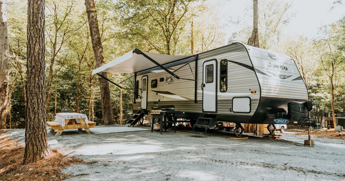 A Jayco travel trailer with its awning out on a wooded, gravel full-hookup site at Ted & Tracy's RV Campground, Washington, Georgia