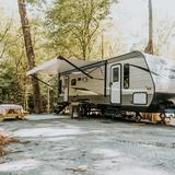 A Jayco travel trailer with its awning out on a wooded, gravel full-hookup site at Ted & Tracy's RV Campground, Washington, Georgia