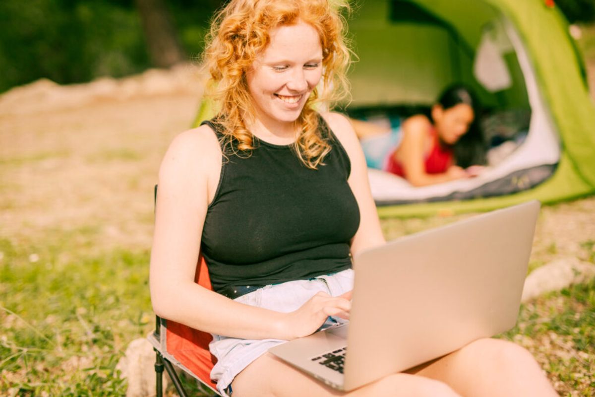 a woman making a booking using reservation software outside of her camping site 
