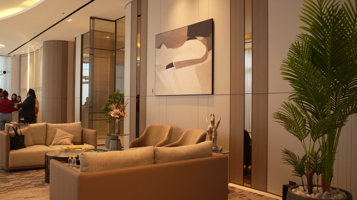 A wide view of the lounge seating with a Bonsai speaker on the panelled wall and a palm in the corner