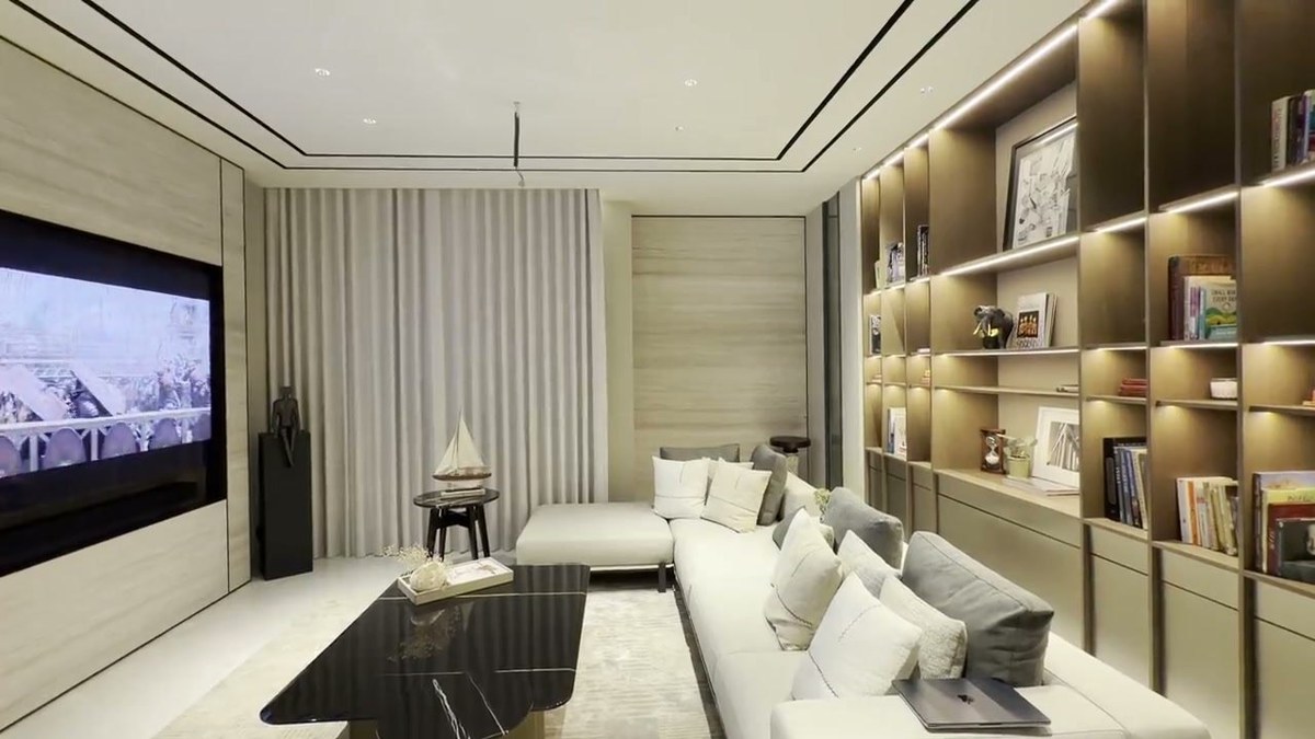 A media lounge with a recessed television, a custom XSCACE LCR soundbar beneath it and a full-height illuminated bookcase along the opposite wall