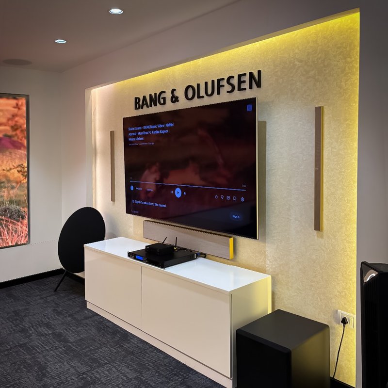 XSCACE QuadCane speakers flanking a demo TV wall inside a Bang & Olufsen showroom