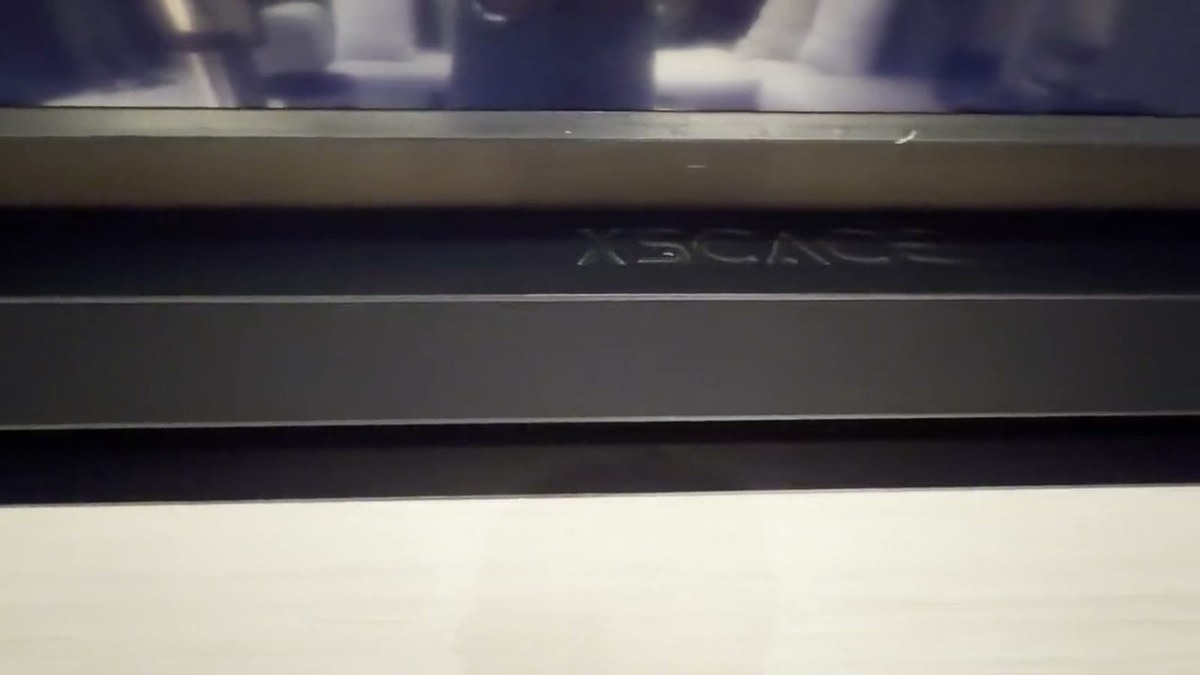 Close detail of the custom XSCACE soundbar showing the embossed XSCACE wordmark on its black anodised face