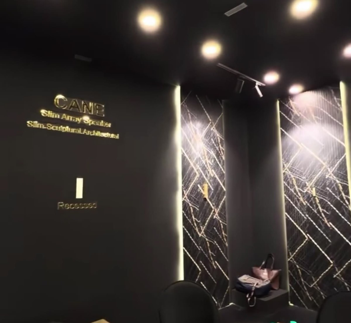 Inside the XSCACE stand at the Architectural Digest Design Show 2025, showing a Cane slim array speaker recessed flush into a marble slat wall so only a narrow vertical line is visible