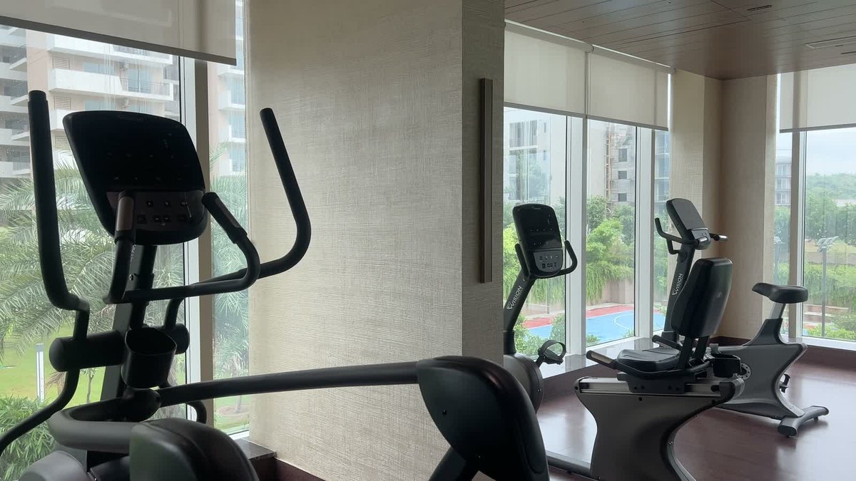 Cardio equipment beside floor-to-ceiling glazing in the clubhouse gym, with an XSCACE QuadCane slim array on the central pier