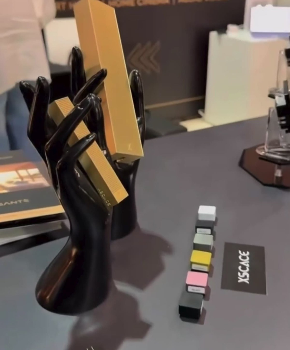 XSCACE slim array speakers displayed in sculptural hand mounts on the GadgEon stand at INDEX Dubai, showing the scale of the ultra-slim profile against a hand