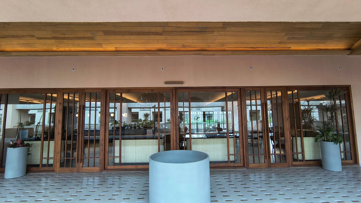 The clubhouse terrace looking toward the folding teak doors and the interior beyond, with large planters and a patterned terrazzo floor