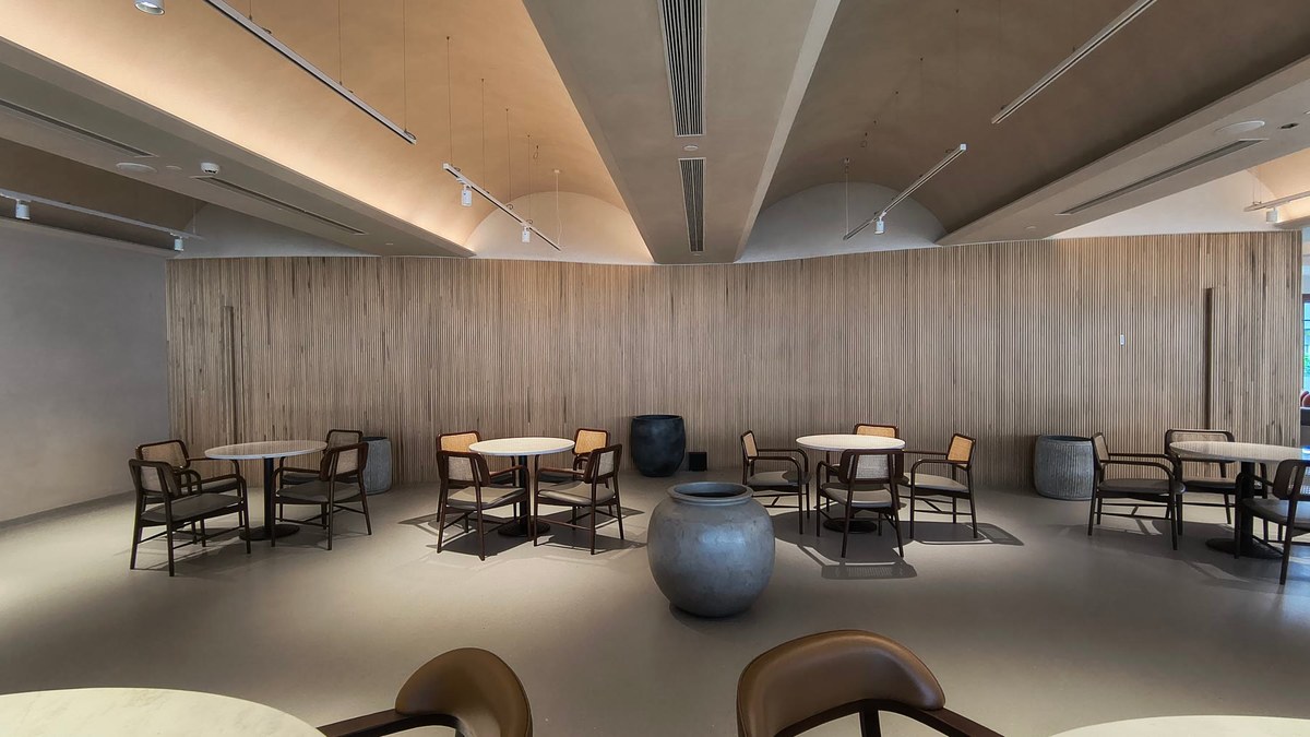 The clubhouse dining room with a curved fluted timber wall, cove-lit ceiling and loose tables