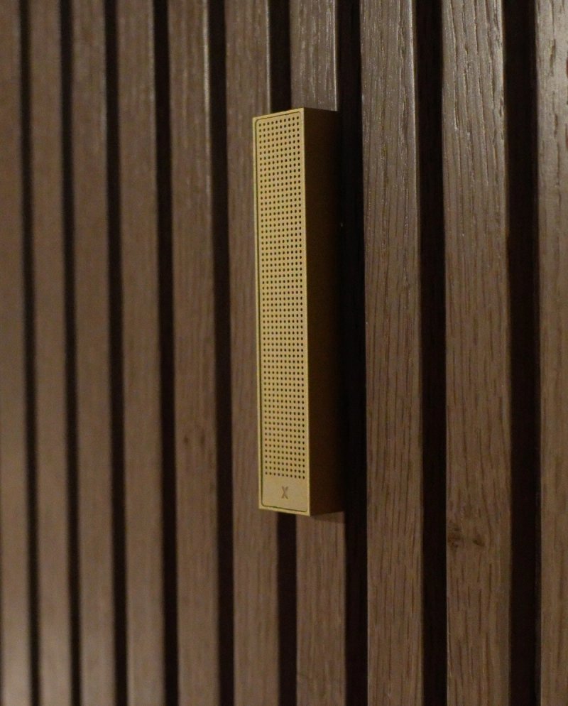 XSCACE Bonsai speaker mounted on a fluted vertical wood-slat foyer wall