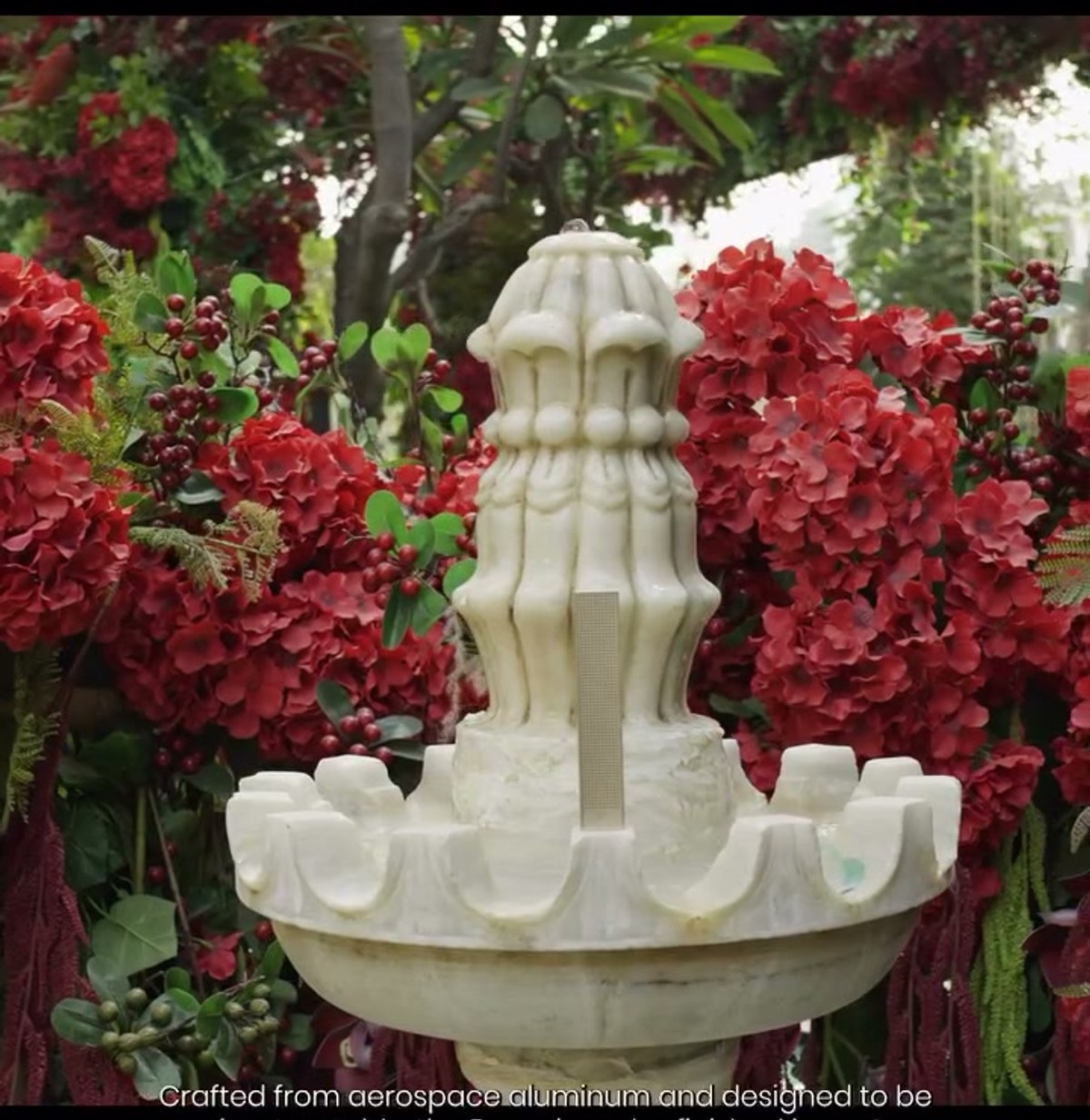 Close-up of the marble fountain speaker install surrounded by red floral garlands