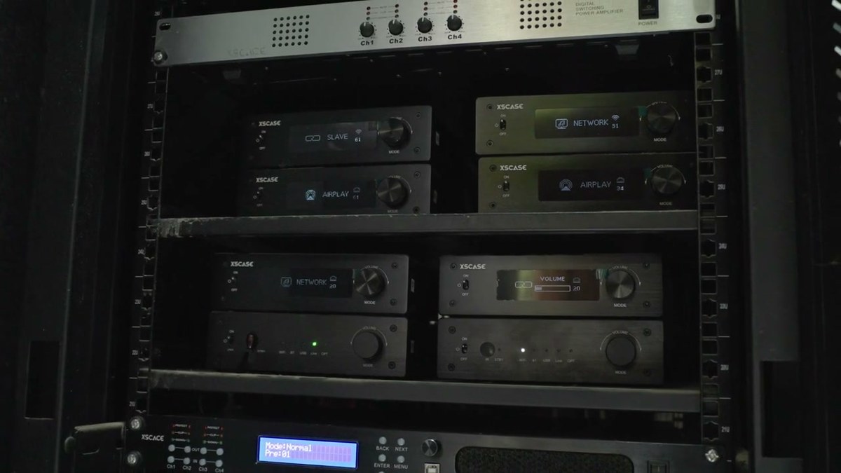 The equipment rack with an XSCACE four-channel power amplifier, networked zone amplifiers and a DSP amplifier showing its preset