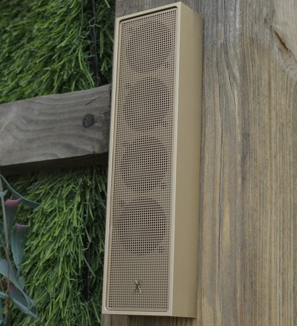 XSCACE Cane speaker mounted on a weathered wood fence in an outdoor garden setting