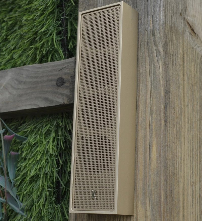 XSCACE Cane speaker mounted on a weathered wood fence in an outdoor garden setting