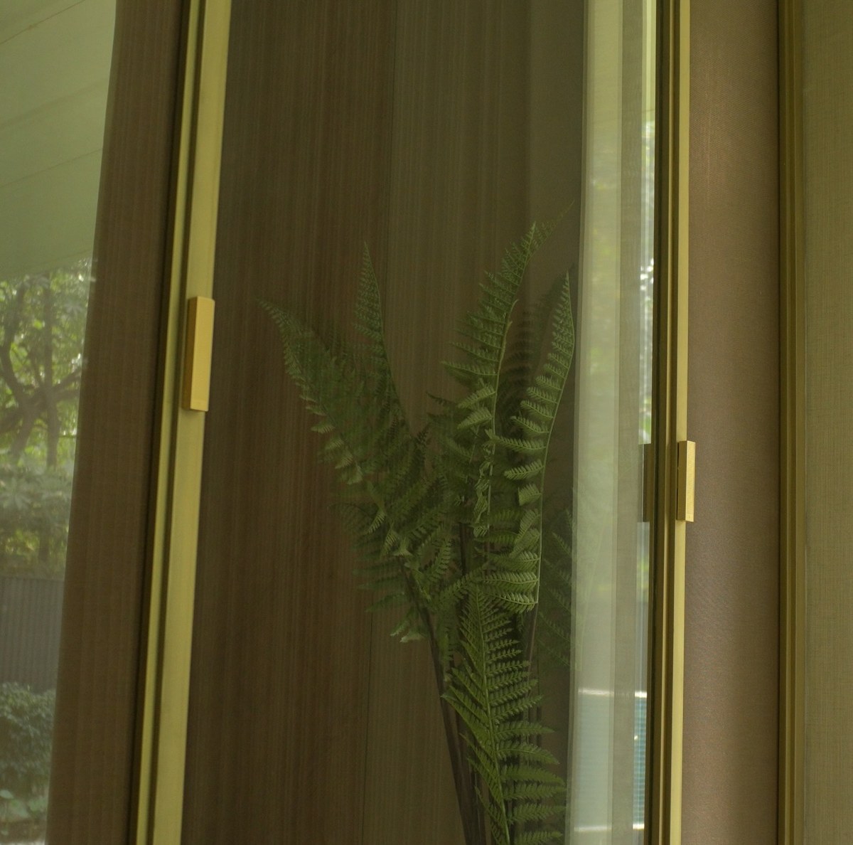 XSCACE Bonsai speaker on a dark walnut wardrobe door beside a bookmatched marble slab wall