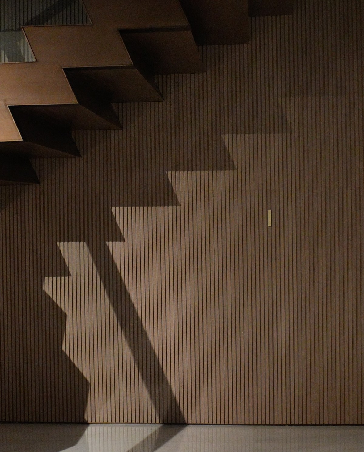 XSCACE Bonsai speaker mounted on a fluted vertical wood-slat foyer wall