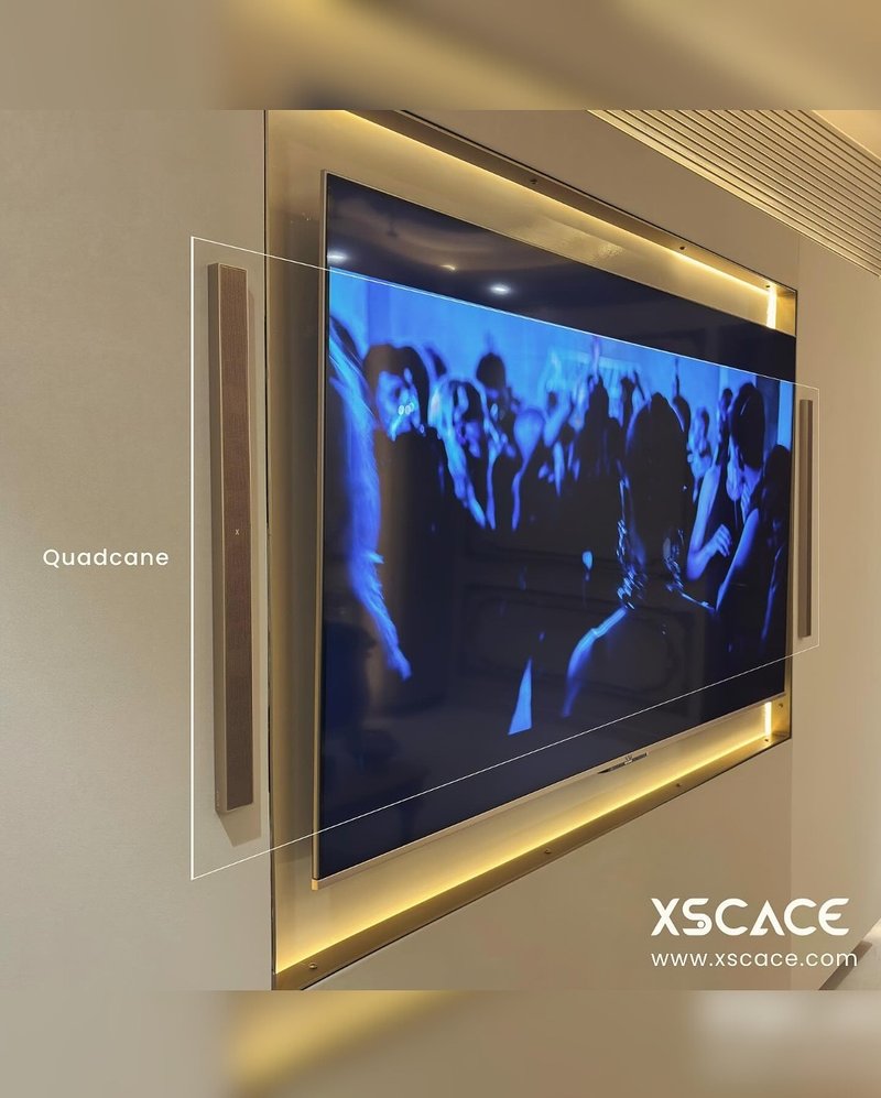 TV wall in a media lounge with an XSCACE Quadcane speaker mounted vertically beside the screen, backlit in gold