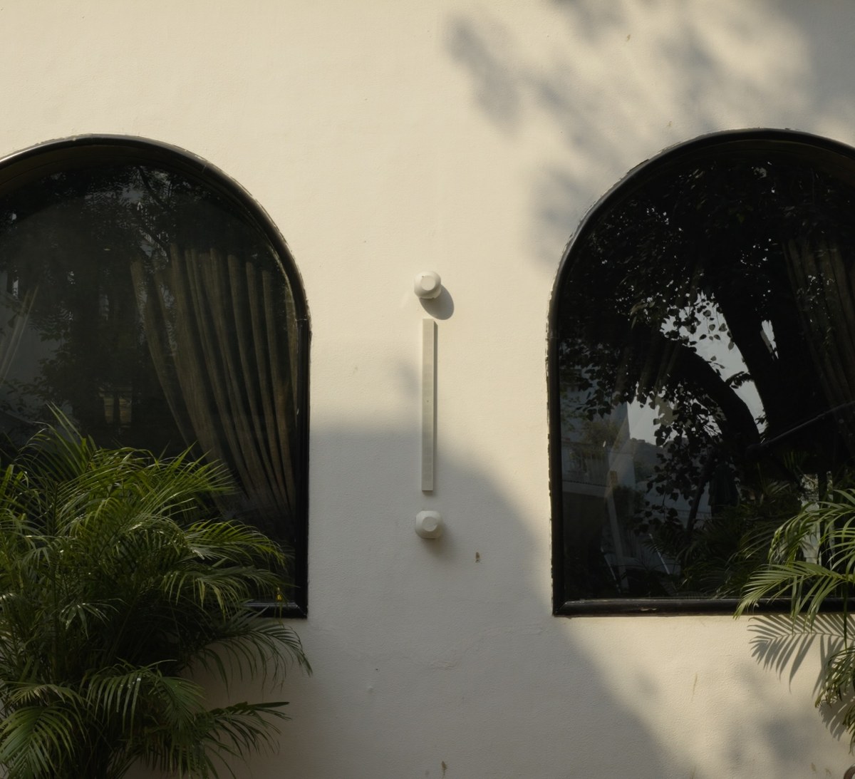 XSCACE QuadCane speaker mounted on a textured stucco restaurant facade between arched windows