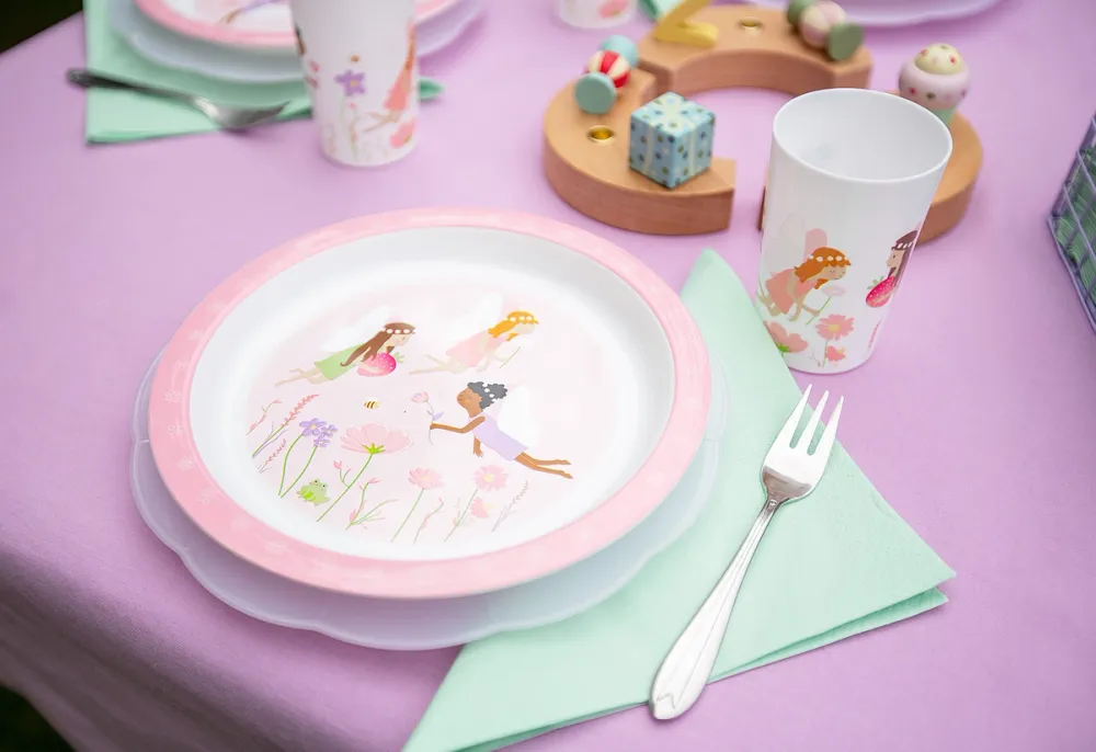 tallerken med små alver eller feer. Lilla duk og bursdagspynt på bordet