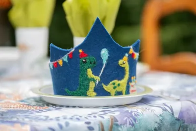 En blå filt-krone med dinosaurer på