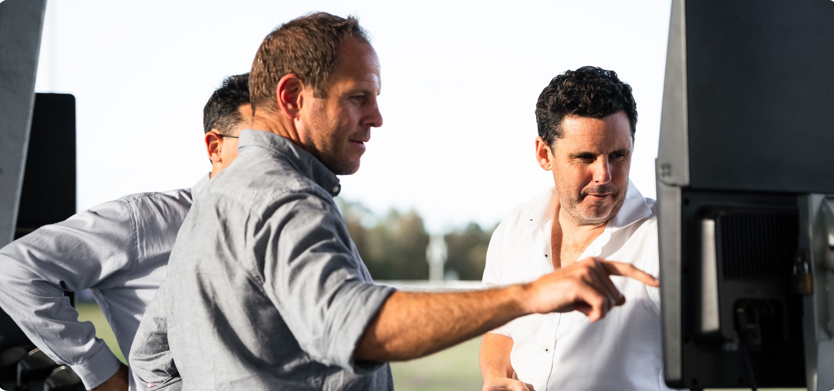 Three men looking at golf monitor