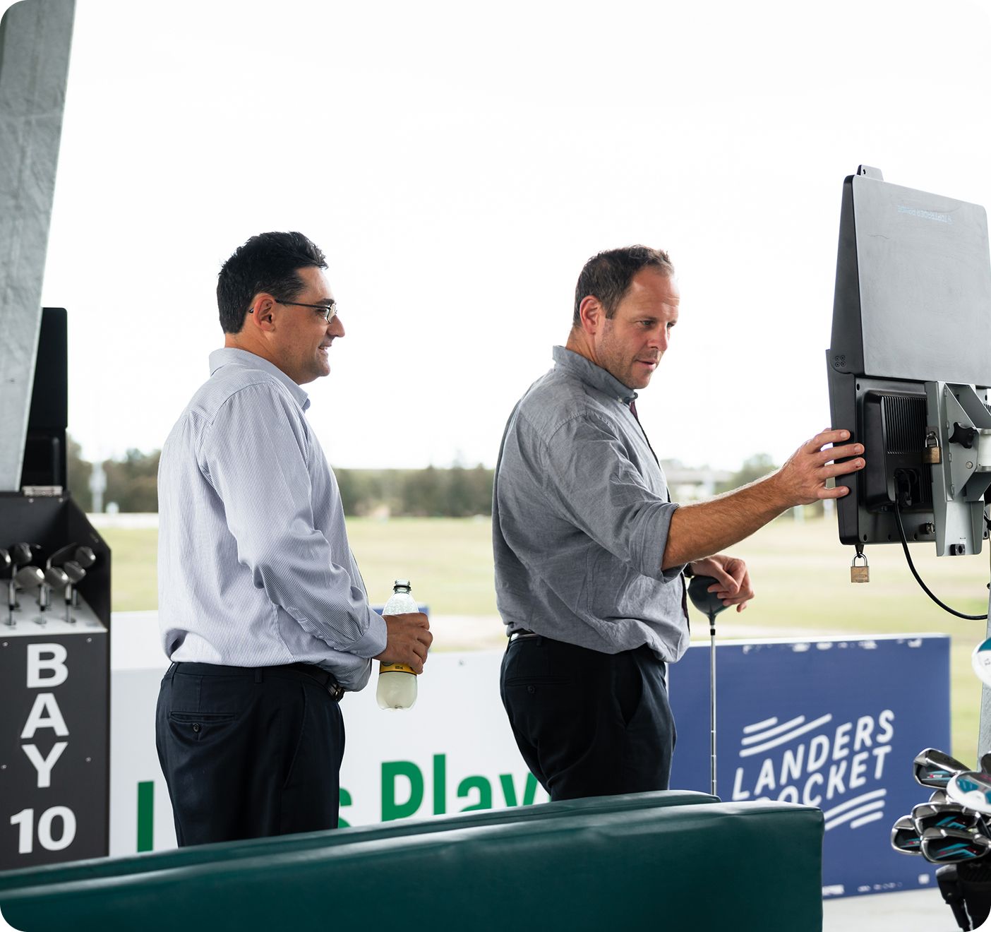 Two men looking at golf monitor
