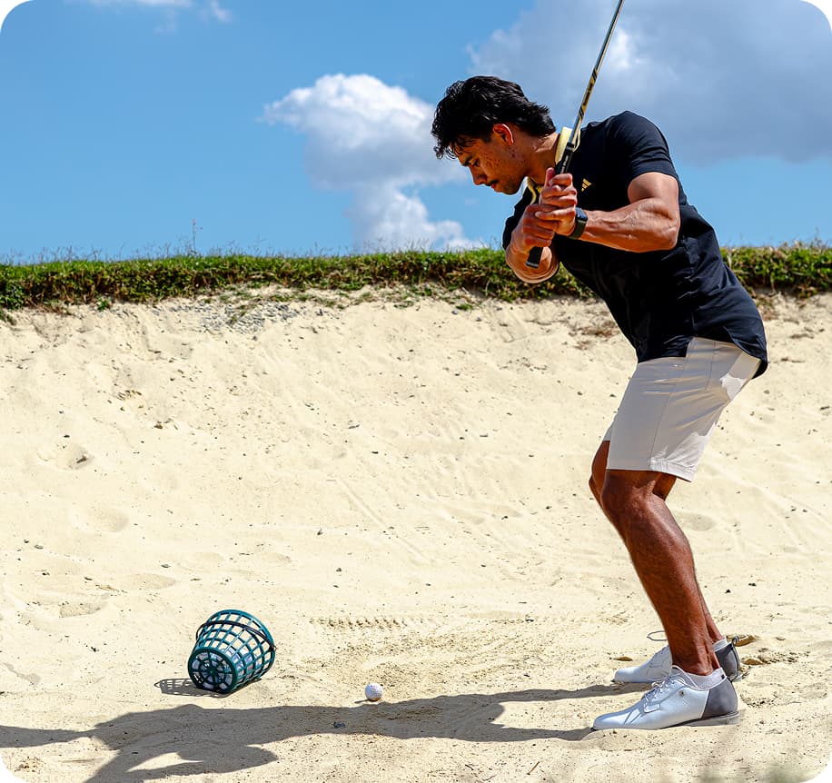 Man swinging golf club on sand