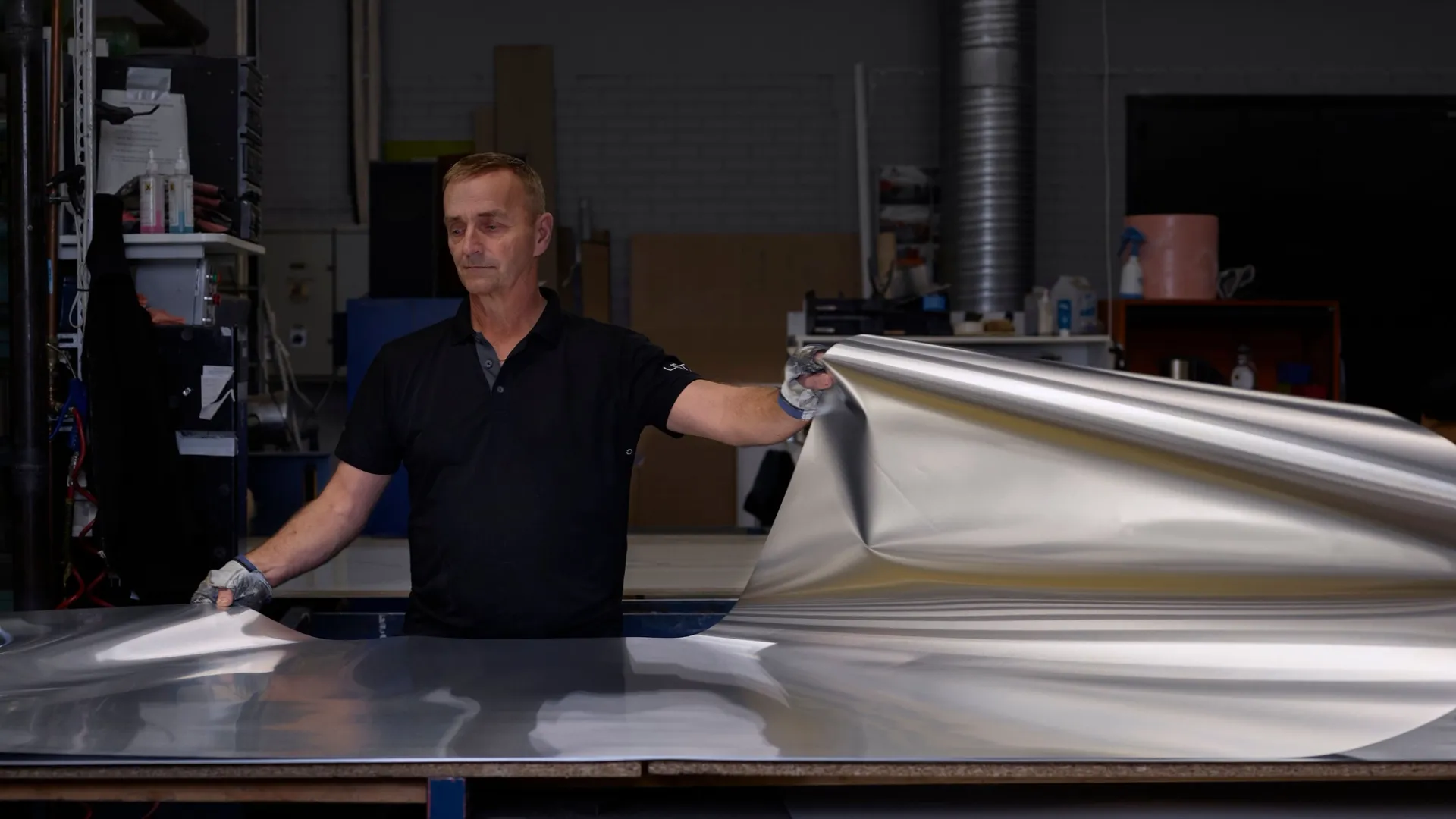 A worker in the Lintex factory lifting a large sheet of material onto a bench