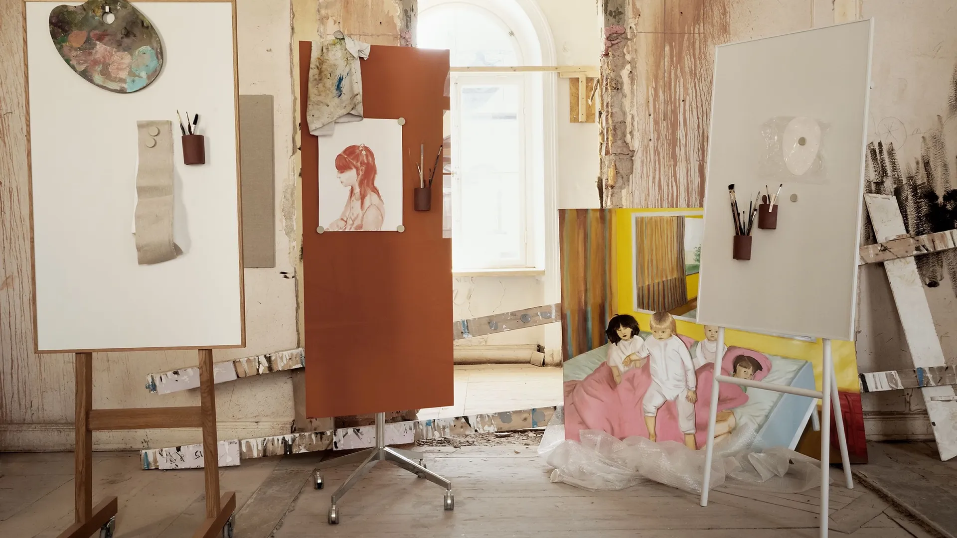 Writing boards and pinned sketches in the studio, with a painting on the floor