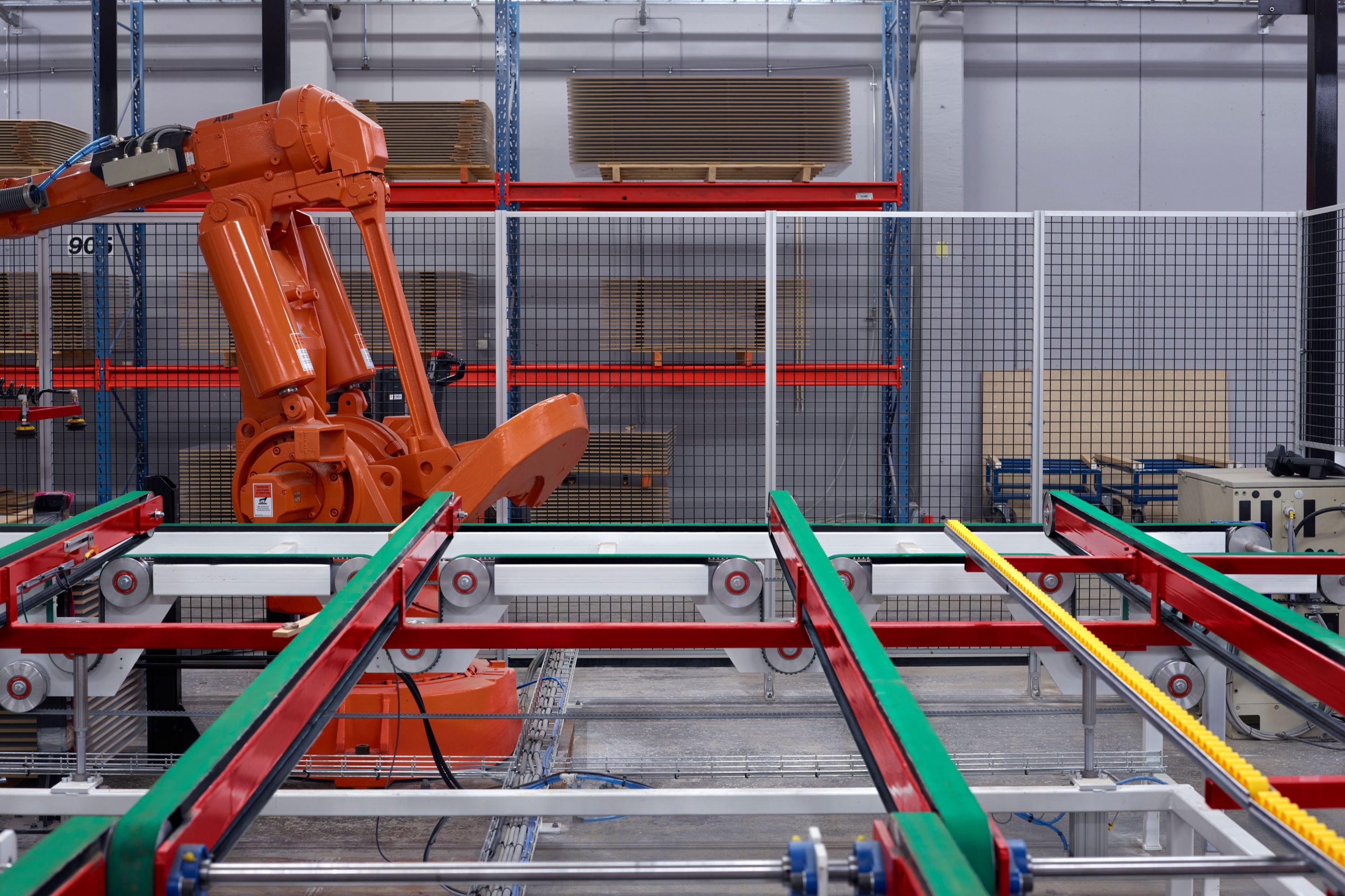 Un robot industriel orange manipule des panneaux sur la ligne de production