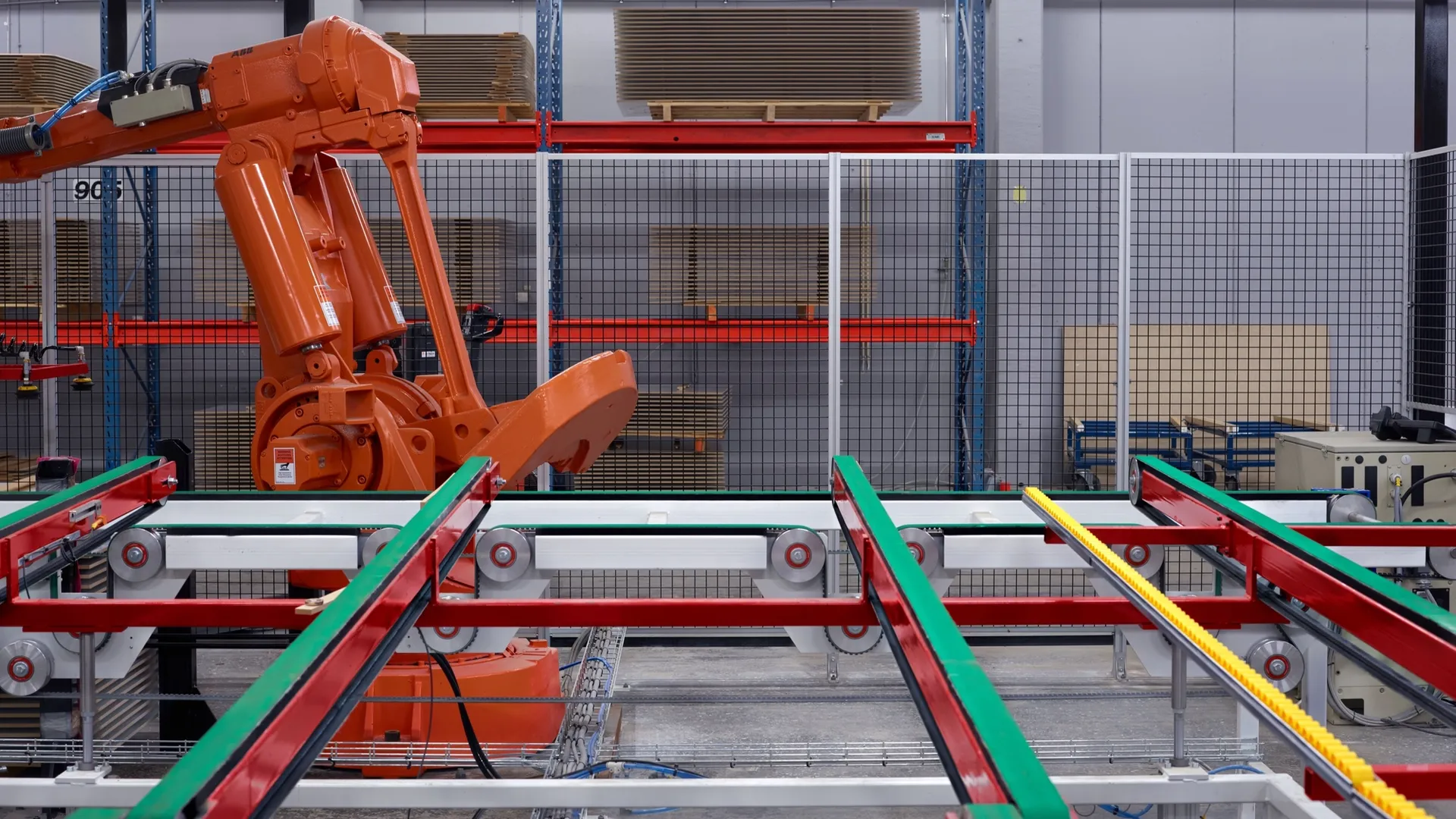 Un robot industriel orange manipule des panneaux sur la ligne de production