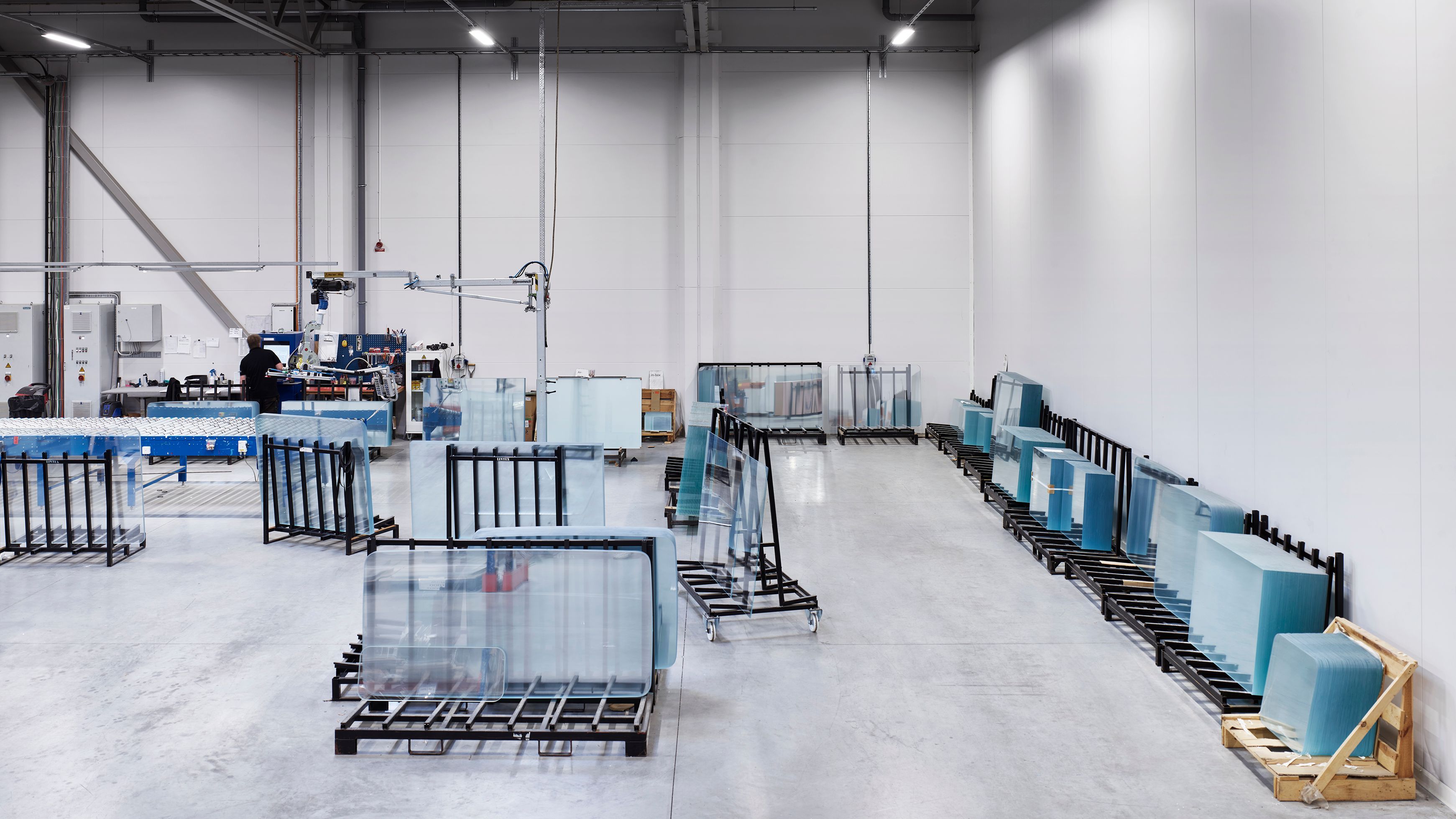 Glass panels in racks inside a bright factory hall.