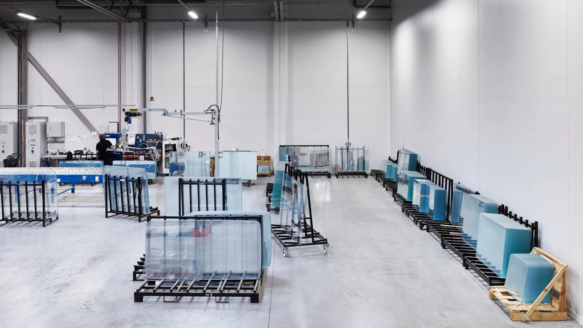 Glass panels in racks inside a bright factory hall.