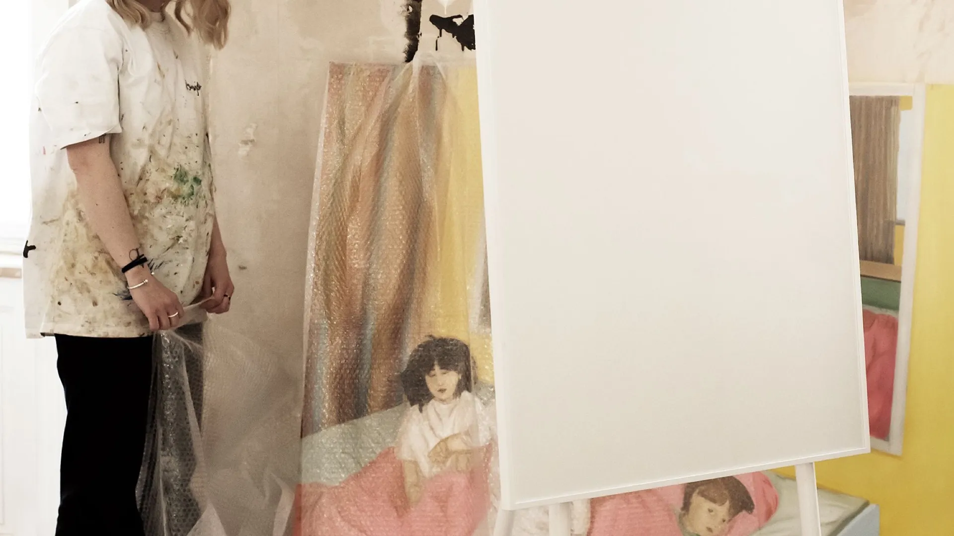 Artist Viola Sparre standing beside a mobile writing board in front of a painting